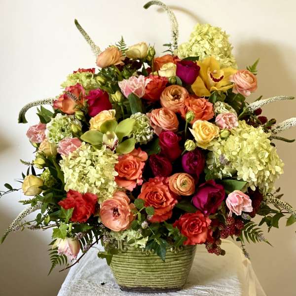 Large mixed bouquet in a green ceramic vase with roses and hydrangeas