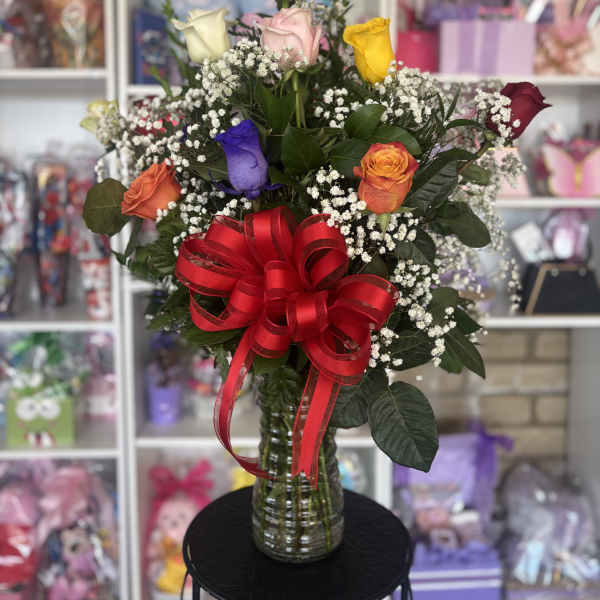 Mixed roses in a glass vase with a red ribbon bow