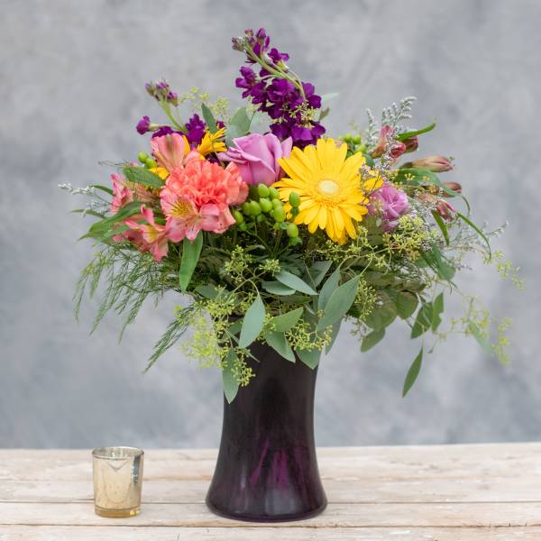 Mixed bouquet in a dark vase with yellow, pink, and purple flowers
