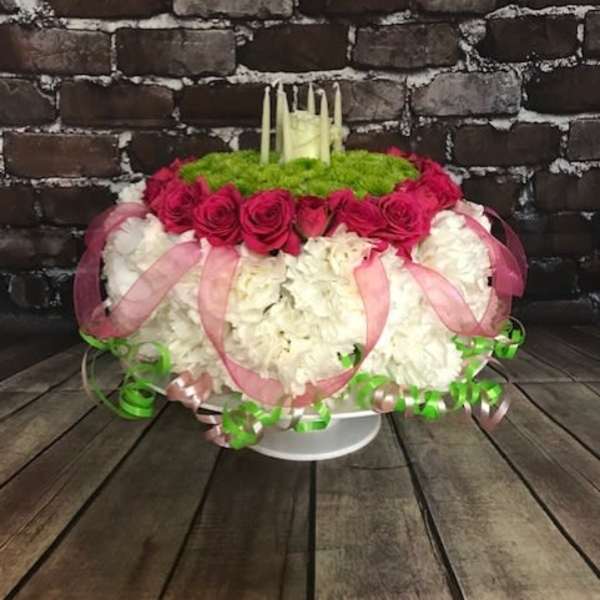 Round floral arrangement with pink roses and white blooms on a pedestal stand