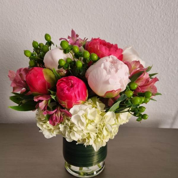 Pink and white peonies with hydrangeas in a glass vase