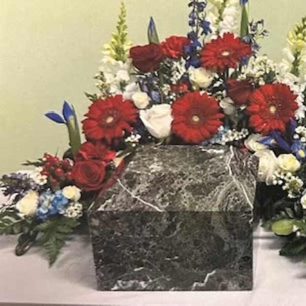 Red, white, and blue floral funeral tribute around a framed photo