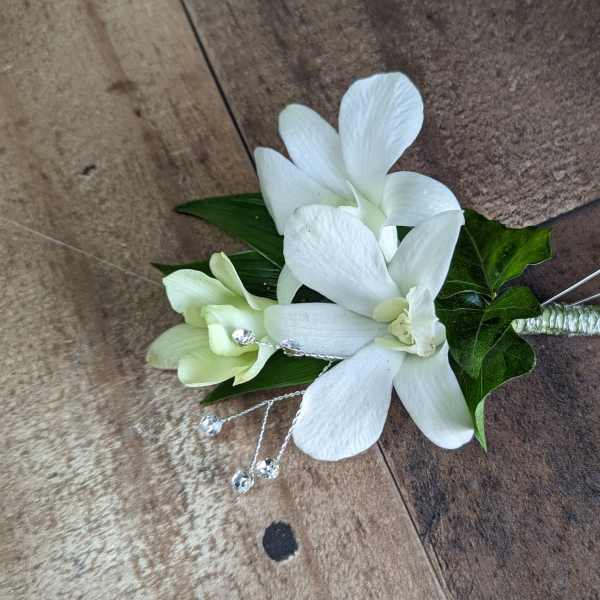 White orchid boutonniere with green leaves and crystal accents