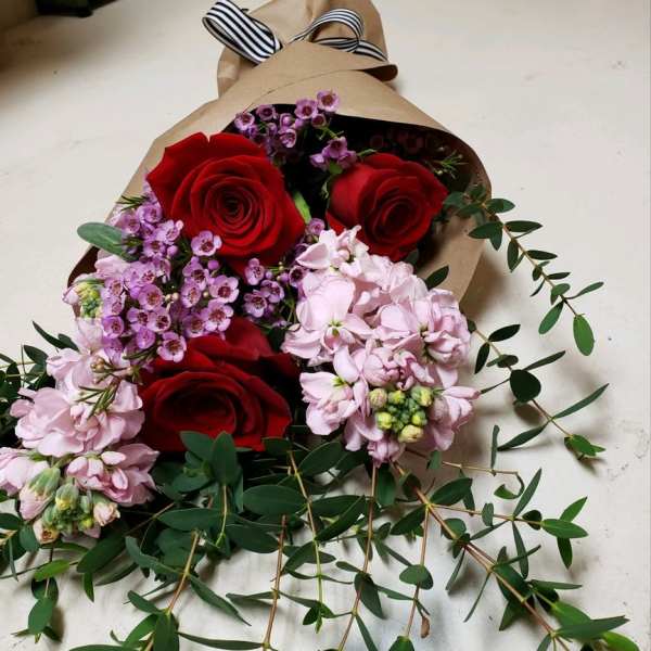 Bouquet of red roses and pink flowers wrapped in brown paper