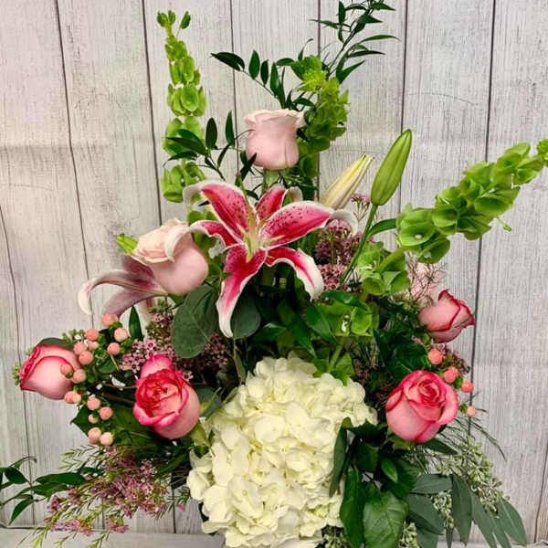 Tall floral arrangement with pink lilies, roses, and white hydrangea in a vase