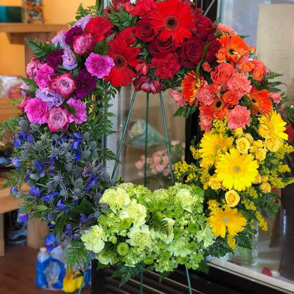 Colorful floral wreath on a stand with red, pink, orange, yellow, and green blooms
