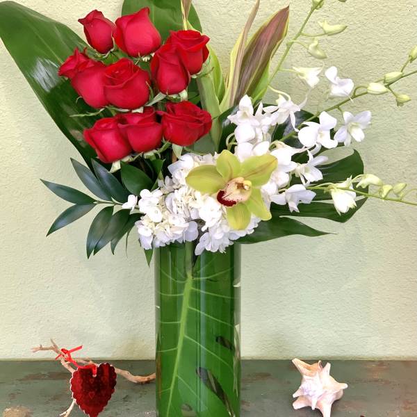 Red roses and white orchids arranged in a tall glass vase