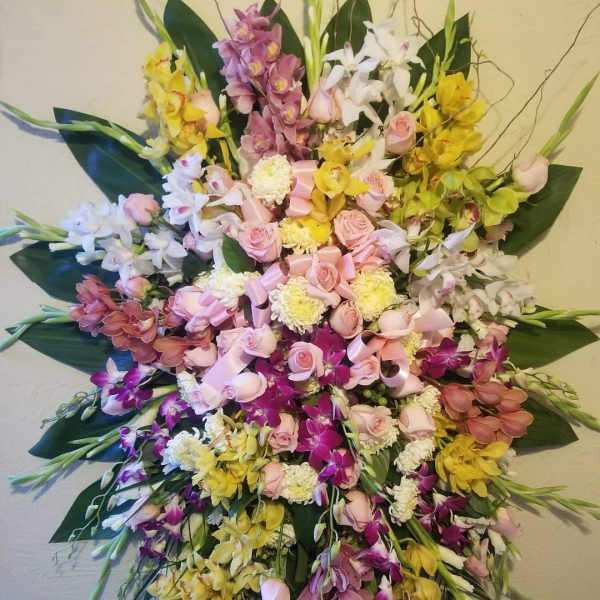 Large cascading bouquet of orchids, roses, and mums in pink, yellow, white, and purple