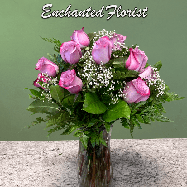 Tall glass vase of pink roses with white filler flowers