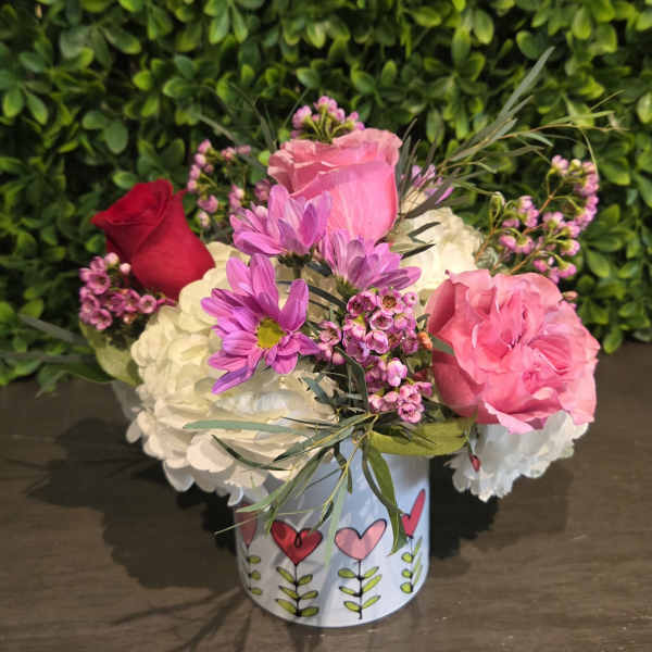 Pink and white flower arrangement in a decorated tin container