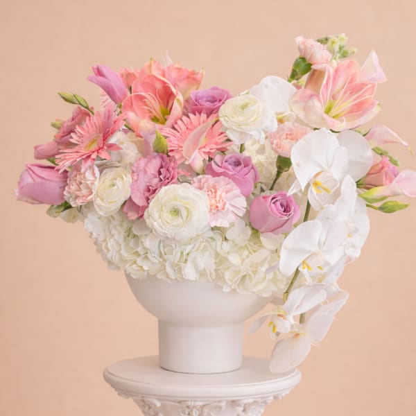 Pink and white floral arrangement in a white pedestal vase