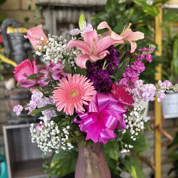 Pink bouquet with lilies, gerbera daisy, and a bright ribbon in a vase