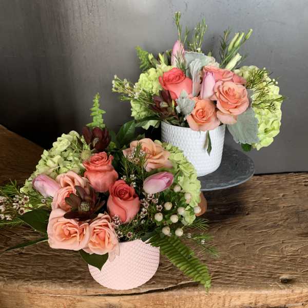 Two rose arrangements in textured pots with pink and peach blooms