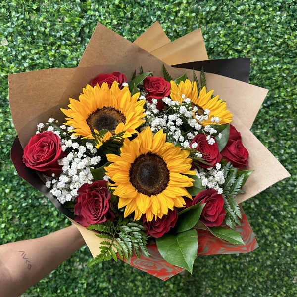 Bouquet of red roses and yellow sunflowers wrapped in brown paper