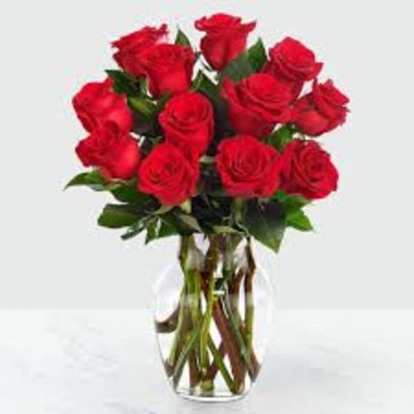 Arrangement of red roses in a clear glass vase with visible stems