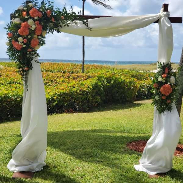 Floral wedding arch with white draping and coral-white flowers