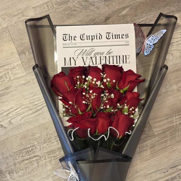 Bouquet of red roses wrapped in black paper with a Valentine card