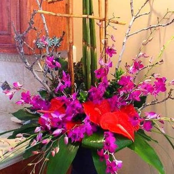 Tall red and purple floral arrangement in a dark vase