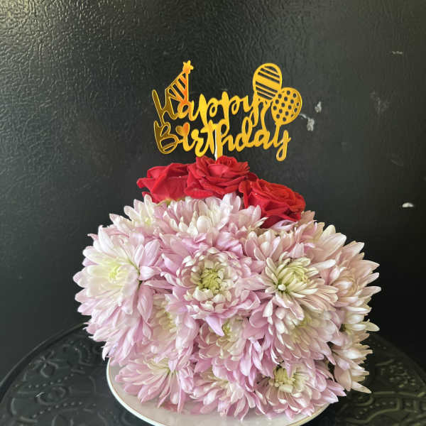 Pink chrysanthemum bouquet with red roses and a birthday topper on a plate