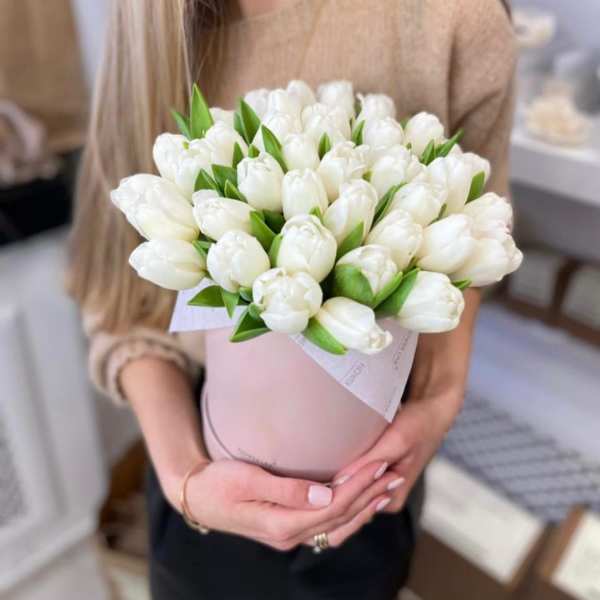 Woman holding a bouquet of white tulips in a pink wrap