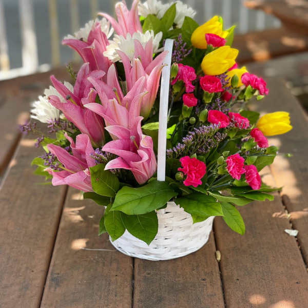 Basket of pink lilies, yellow tulips, and mixed blooms
