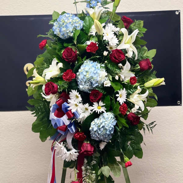 Standing floral spray with red roses, white lilies, and blue hydrangeas