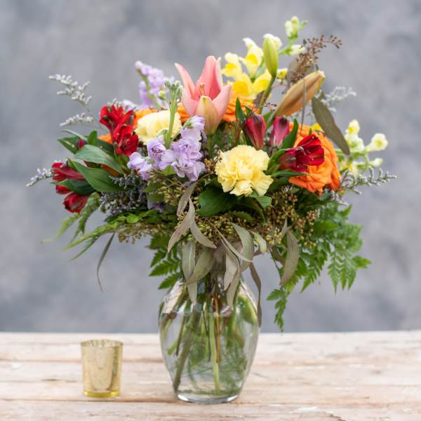 Mixed bouquet in a glass vase with pink, yellow, red, and orange flowers