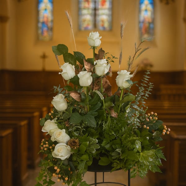 White roses arranged with greenery in a church setting