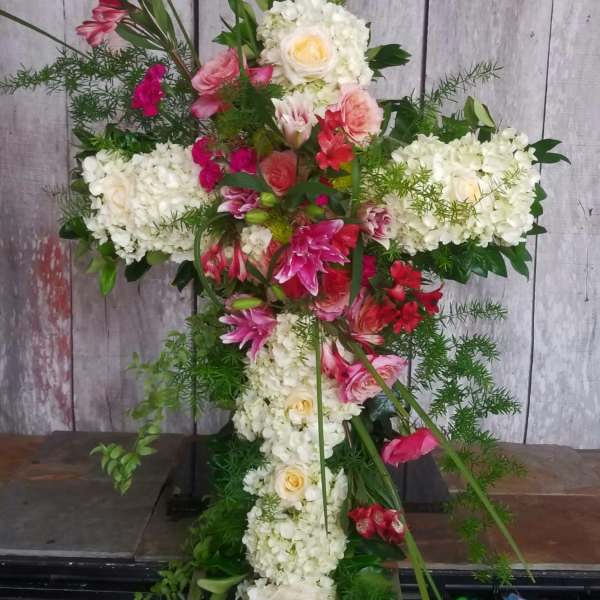 Cross-shaped floral arrangement with white hydrangeas and pink flowers