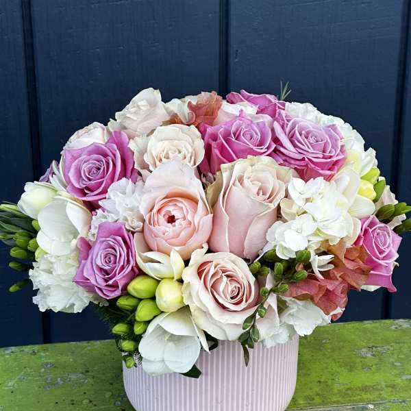 Pink and white rose bouquet in a ribbed blush vase