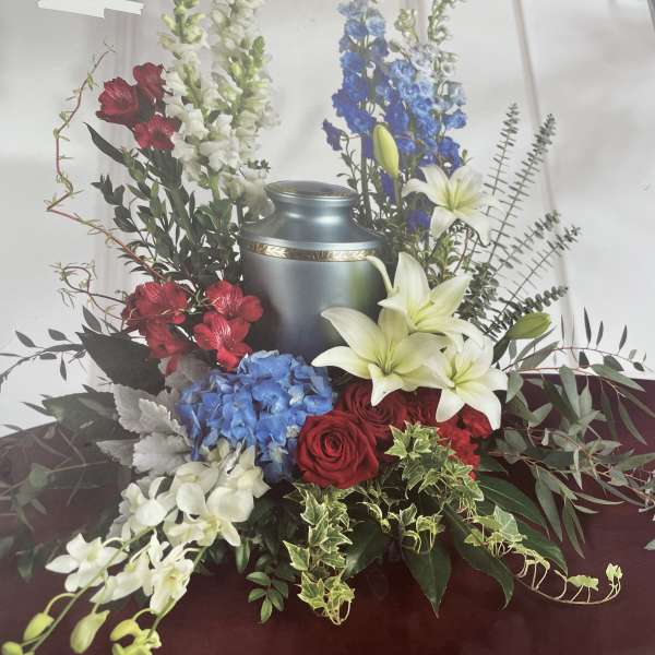 Funeral urn surrounded by red, white, and blue flowers