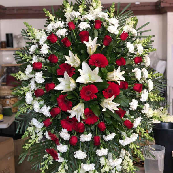 Large red and white funeral spray with roses, lilies, and gerbera daisies