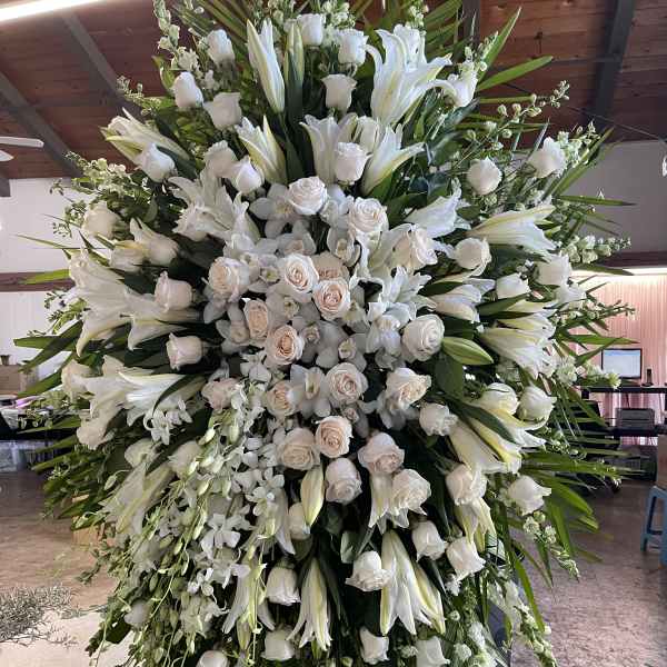 Large white funeral spray with roses and lilies on an easel