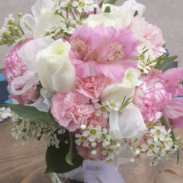 Pink and white bouquet in a clear glass vase with ribbon