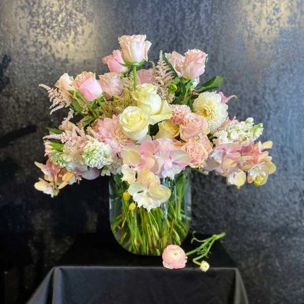 Pink and cream roses with orchids in a glass vase