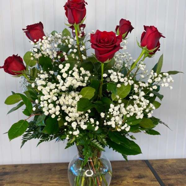 Red roses arranged in a clear glass vase with white baby's breath
