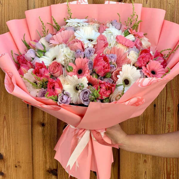 Pink bouquet of mixed flowers wrapped in pastel paper