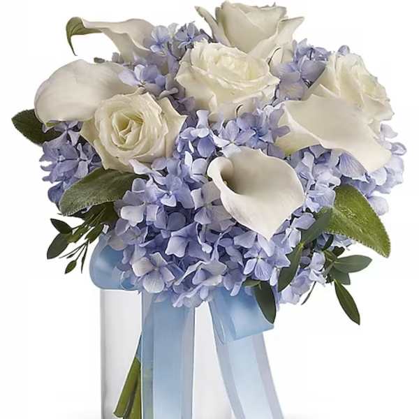 White roses and calla lilies in a glass vase with a blue ribbon