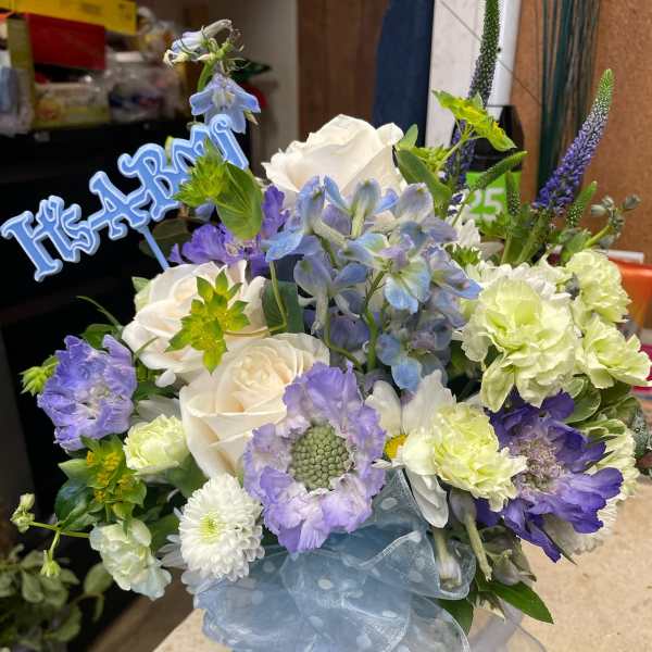 Blue and white floral arrangement in a white hatbox with a ribbon