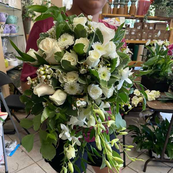 Large white bouquet with roses and orchids, held by a person