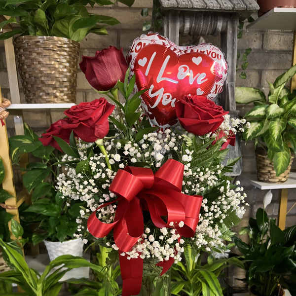 Red roses in a glass vase with a heart balloon and red ribbon
