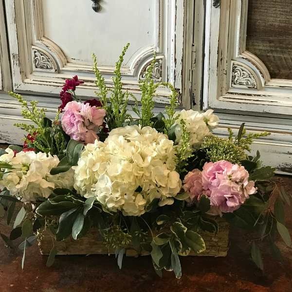 Low floral arrangement with white and pink blooms in a rectangular container