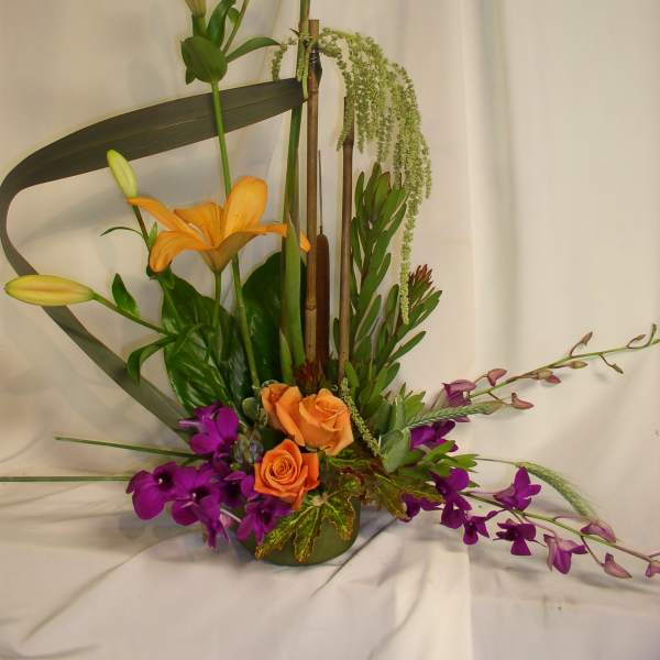 Tall floral arrangement with orange lilies, roses, and purple orchids