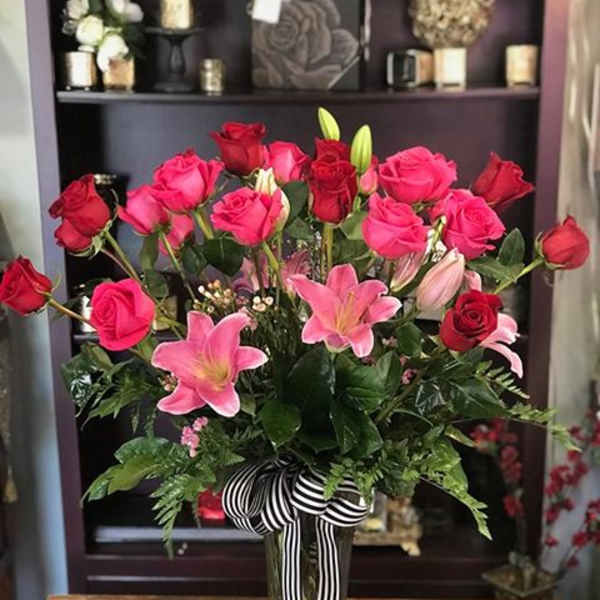 Pink and red roses with pink lilies in a glass vase