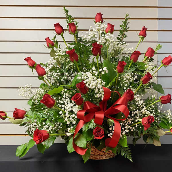 Basket arrangement of red roses with white baby's breath and a red ribbon