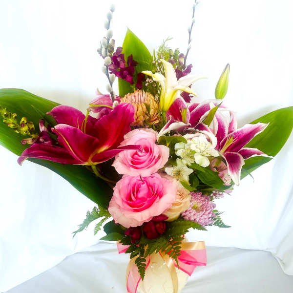 Pink and white mixed flower bouquet in a cream vase with ribbon