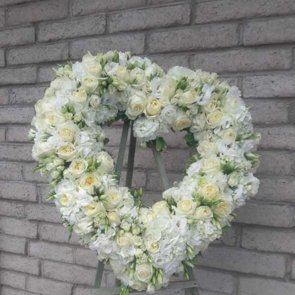 Heart-shaped white floral wreath on a stand