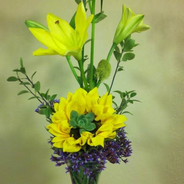 Tall yellow lily arrangement in a clear glass vase