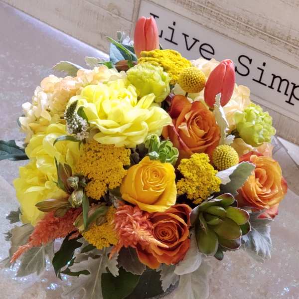 Yellow and orange flower arrangement in a low vase
