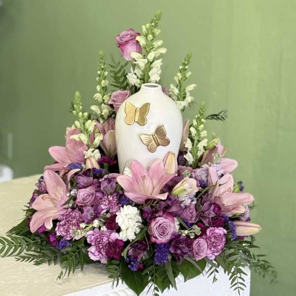 Pink and purple floral arrangement around a white butterfly vase
